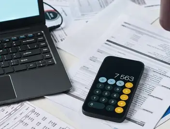 Laptop i kalkulator na dokumentach finansowych – planowanie i testowanie elektronicznego obiegu faktur w systemie workflow.