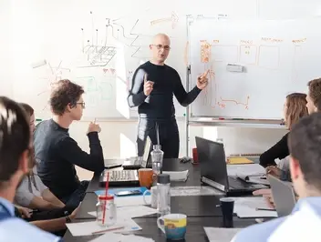 Zespół pracowników w sali konferencyjnej analizujący procesy i obieg dokumentów w organizacji rozproszonej