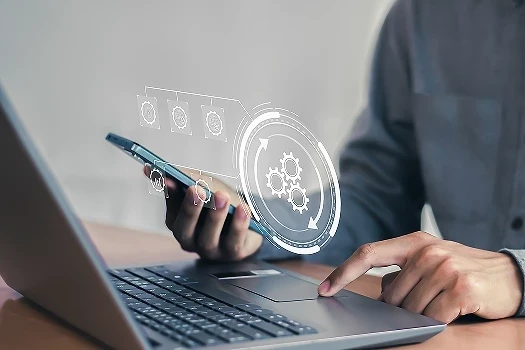 Pracownik przed laptopem z telefonem w ręce poszukujący systemów wspierających