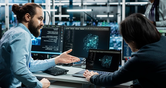 Dwóch specjalistów IT analizujących trójwymiarową wizualizację danych na laptopie w nowoczesnym centrum danych