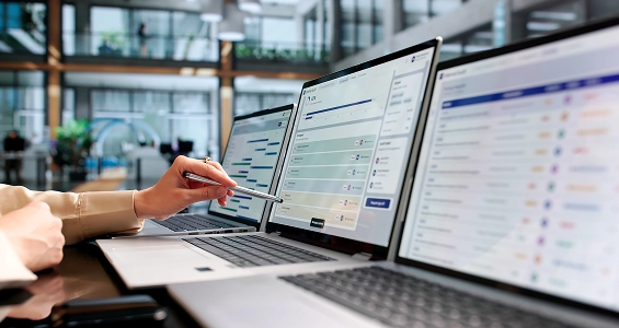 Ręka wskazująca długopisem interfejs programu na laptopie, ilustrujący zarządzanie danymi cyfrowego paszportu produktu