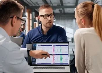 Trzy osoby w biurze analizują dane na ekranie laptopa, co może ilustrować weryfikację informacji w ramach cyfrowego paszportu produktu