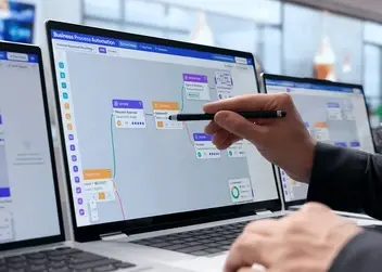 Osoba wskazująca rysikiem na ekranie laptopa diagram przepływu workflow w narzędziu do automatyzacji procesów biznesowych low-code.
