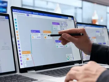 Osoba wskazująca rysikiem na ekranie laptopa diagram przepływu workflow w narzędziu do automatyzacji procesów biznesowych low-code.